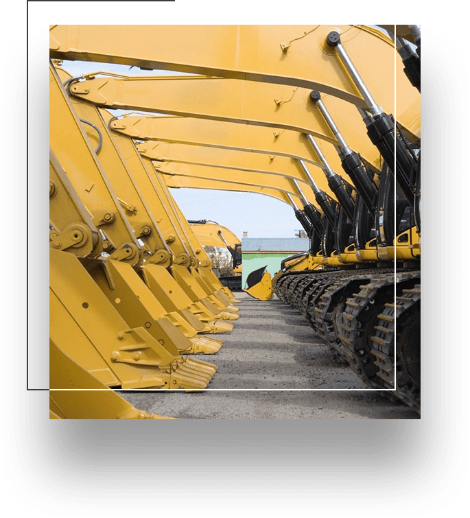 A row of yellow construction equipment parked in front of the ocean.